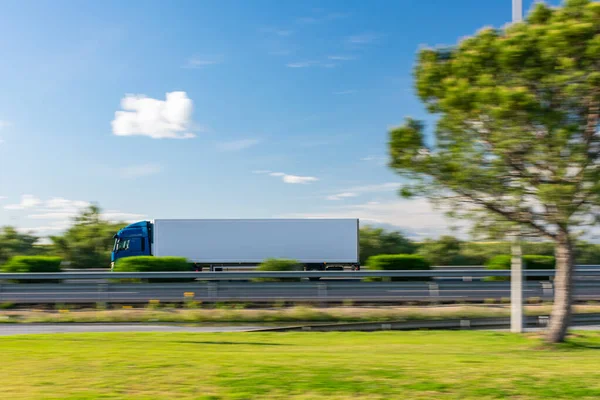 Truck with refrigerated semi-trailer driving on the highway with a blue sky with some clouds