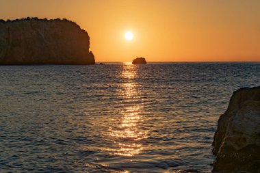 Güneşin doğuşu kayalık bir sahildeki suya yansıdı.