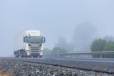 Yoğun sisli bir günde, yarı karavanlı bir kamyon yolda gidiyor.