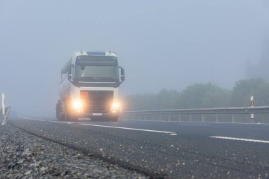 Tank truck with dangerous goods circulating on the highway on a day of thick fog. clipart