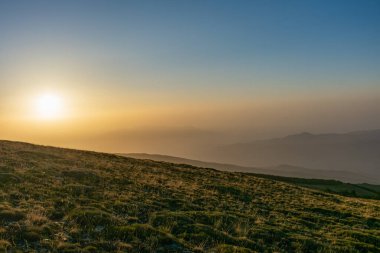 Arka planda Sierra Nevada 'nın zirveleri olan bir çayırda gün doğumu