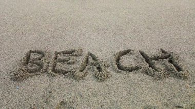 word plaj / deniz dalga tarafından iptal kum üzerinde yazılı kelime beach 