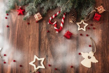 Kahverengi ahşap arka plan görünümlü Noel süslemeleri ve köknar dalları