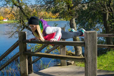Güzel bir kız bir ince rakam siyah tayt ve parlak pembe ceket ile güneşli havalarda sonbahar parkta spor oynuyor.