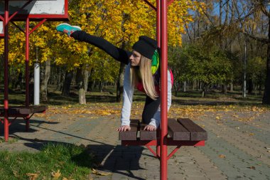 Güzel bir kız bir ince rakam siyah tayt ve parlak pembe ceket ile güneşli havalarda sonbahar parkta spor oynuyor.