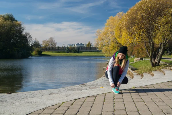 Güzel bir kız bir ince rakam siyah tayt ve parlak pembe ceket ile güneşli havalarda sonbahar parkta spor oynuyor.