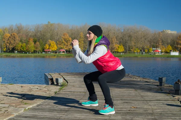 Güzel bir kız bir ince rakam siyah tayt ve parlak pembe ceket ile güneşli havalarda sonbahar parkta spor oynuyor.