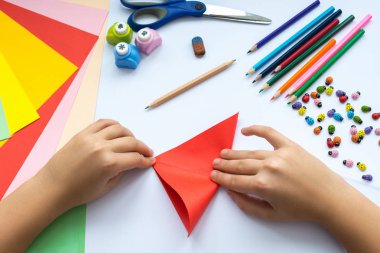 Kırmızı kağıttan origami kuş çocuk ellerin yaptığını.