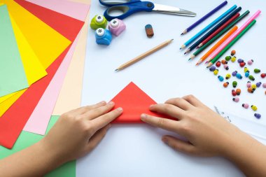 Kırmızı kağıttan origami kuş çocuk ellerin yaptığını.