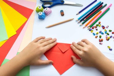 Kırmızı kağıttan origami kuş çocuk ellerin yaptığını.