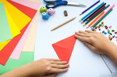 Kırmızı kağıttan origami kuş çocuk ellerin yaptığını.