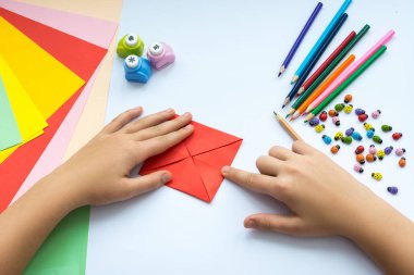 Kırmızı kağıttan origami kuş çocuk ellerin yaptığını.