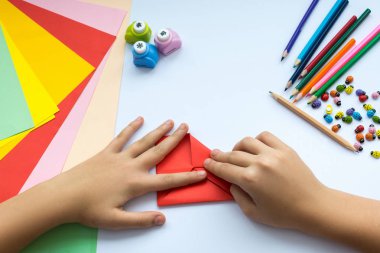 Kırmızı kağıttan origami kuş çocuk ellerin yaptığını.