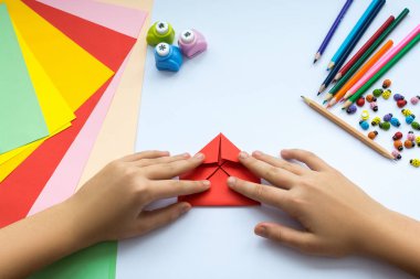 Kırmızı kağıttan origami kuş çocuk ellerin yaptığını.