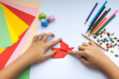 Kırmızı kağıttan origami kuş çocuk ellerin yaptığını.