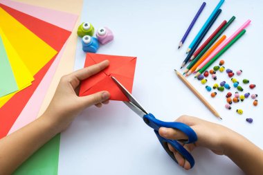 Kırmızı kağıttan origami kuş çocuk ellerin yaptığını.
