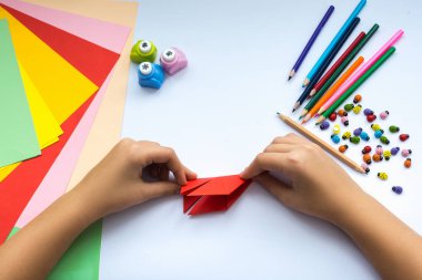 Kırmızı kağıttan origami kuş çocuk ellerin yaptığını.
