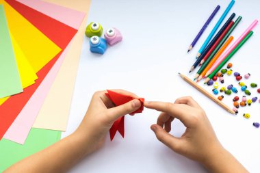 Kırmızı kağıttan origami kuş çocuk ellerin yaptığını.