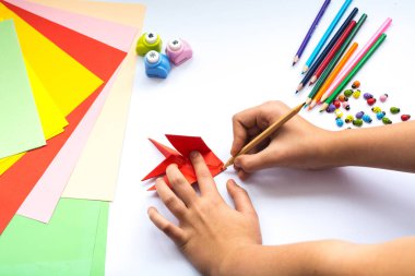 Kırmızı kağıttan origami kuş çocuk ellerin yaptığını.