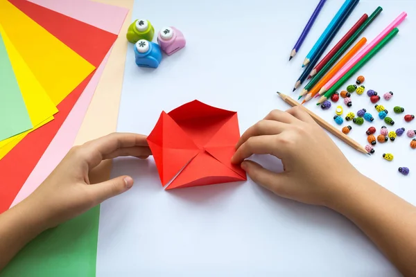 Kırmızı kağıttan origami kuş çocuk ellerin yaptığını.