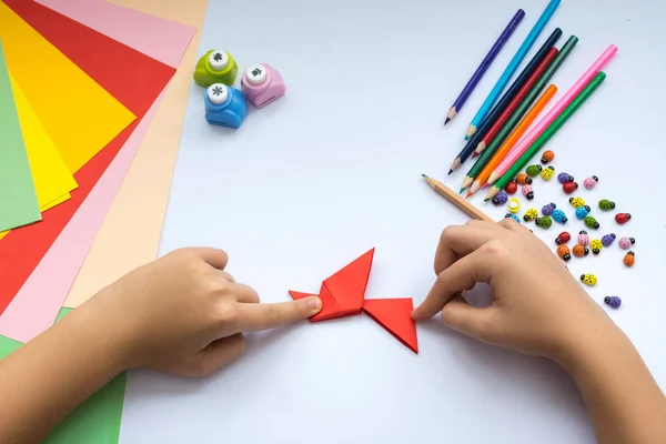 Le mani da bambini fanno l'uccello origami di carta rossa . — Foto Stock