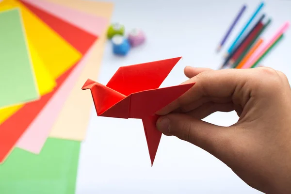 Kırmızı kağıttan origami kuş çocuk ellerin yaptığını.