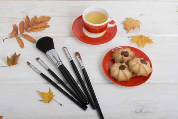 fırçalar için kırmızı fincan çay, makyaj, çerezleri sonbahar yaprakları süslemeleri