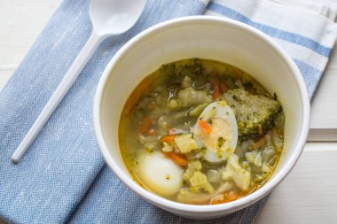 brokolla ve Bıldırcın yumurta tek kullanımlık bir plaka, plastik kaşık sebze çorbası