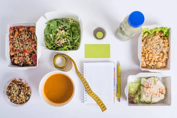 Sağlıklı beslenme planı. Taze günlük yemek teslim. Bir restoran gıda, sebze, et ve meyve folyo kutularında, detoks smuz, kartvizit, not defteri ve kalem Beyaz ahşap zemin üzerinde.