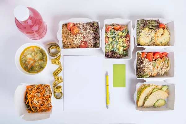 Sağlıklı beslenme planı. Taze günlük yemek teslim. Bir restoran gıda, sebze, et ve meyve folyo kutularında, detoks su, kartvizit, not defteri ve kalem beyaz arka plan üzerinde.