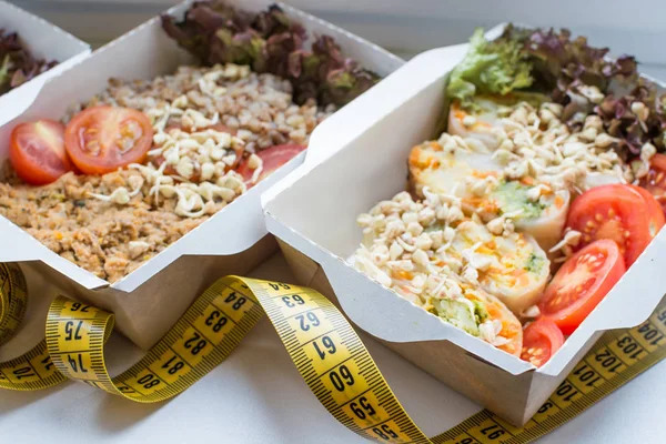 Nourriture végétalienne pour la perte de poids dans des boîtes et un ruban à mesurer. gros plan avec un focus doux — Photo