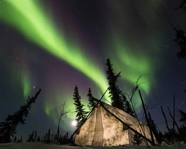 Camping in an old canvas tent under the polar arctic aurora