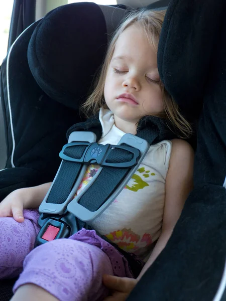A toddler child sleeps in a comfortable and safe car seat while travelling