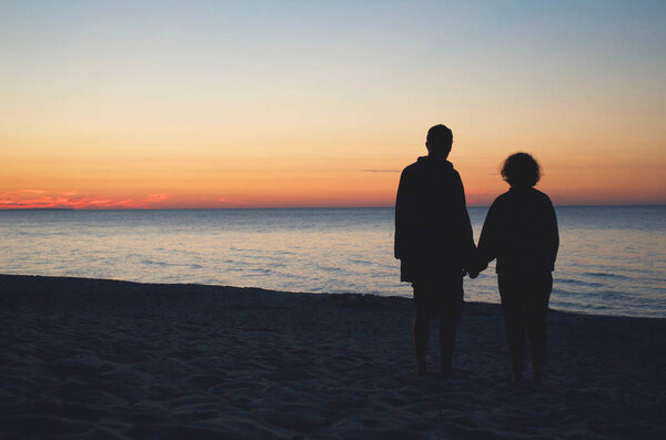 Couple Holding Hands At Sunset At Beach