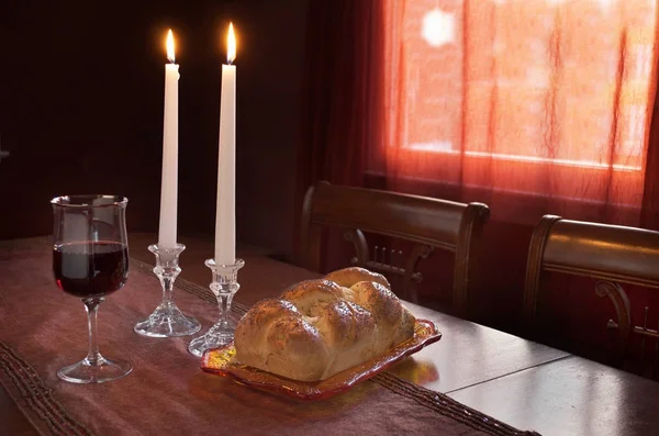 Shabbat yemek Challah içerir veya yumurta ekmek, kırmızı şarap ve yemek odasında iki yanan mumlar batımında örgülü