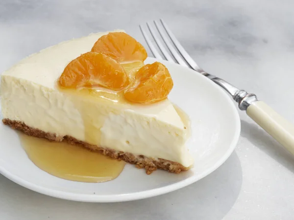 Bir dilim ev yapımı peynirli kek üzerine portakal soslu mandalina ezmesi ve badem ezmesi.  