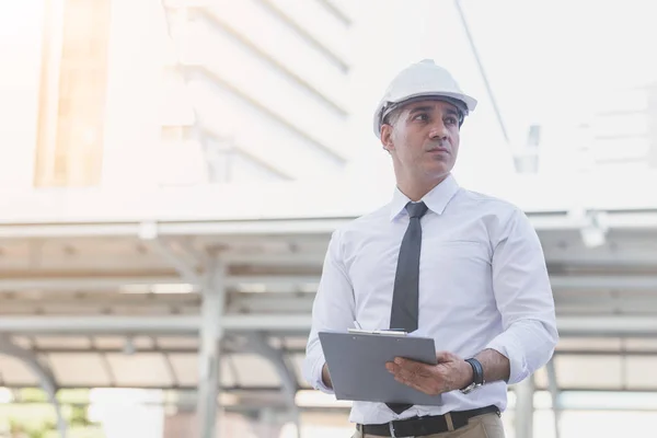 Empresarios e ingenieros en pie sosteniendo documentos de acuerdo . — Foto de Stock