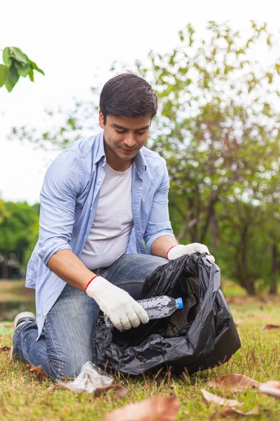 Muž dobrovolník vybrat odpadky láhev plast vyčistit prostředí v zeleném parku. — Stock fotografie