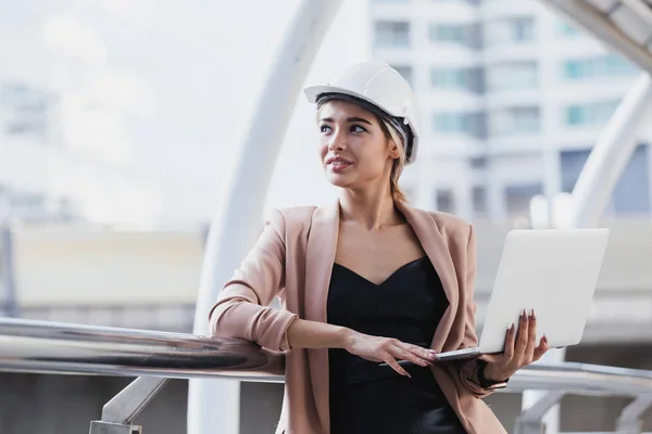 Joven hermosa mujer ingeniero casco blanco de pie trabajando con el ordenador portátil . — Foto de Stock