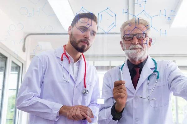 Zwei Ärzte schreiben Formel zur Analyse von Daten auf Glastafel. — Stockfoto