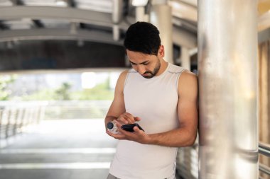 Yakışıklı adam atlet beyaz gömlek ve egzersiz sonrası akıllı telefon kullanıyor..