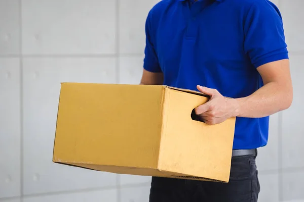 Man blauw shirt holding box bezorgservice. — Stockfoto