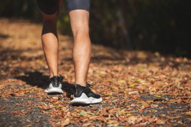 Koşucu spor ayakkabılarıyla bacaklarını kapat. Ormanda koşan erkek..