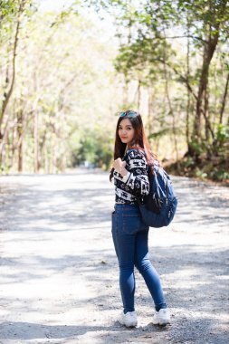 Sırt çantalı Asyalı kadın sonbahar ormanında poz veriyor, yürüyüş konsepti..