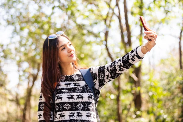 快乐的女人自己在森林里用智能手机旅行拍照. — 图库照片