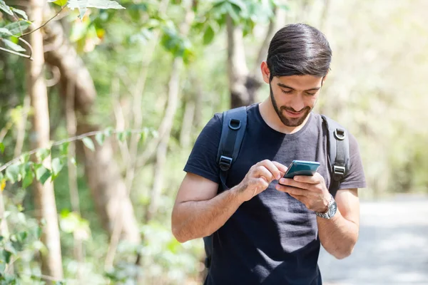 Junger Mann mit Handy unterwegs im Wald. — Stockfoto