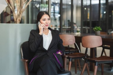 İş kadını ofisteki cep telefonundan mutlu bir şekilde bahsediyor..