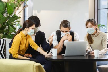 Hijyenik maske takan bir grup iş adamı çalışma odası planlamasında konuşuyorlar..