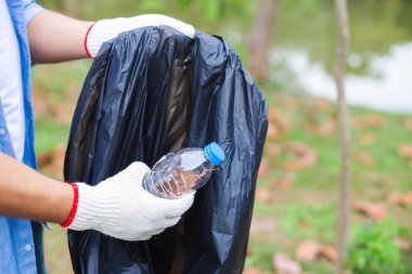 Kapalı kapılar ardında genç gönüllüler. Plastik şişeyi çöp poşetlerine koyup park alanını temizliyor, plastiği düşürüyor ve küresel ısınmayı azaltıyor..