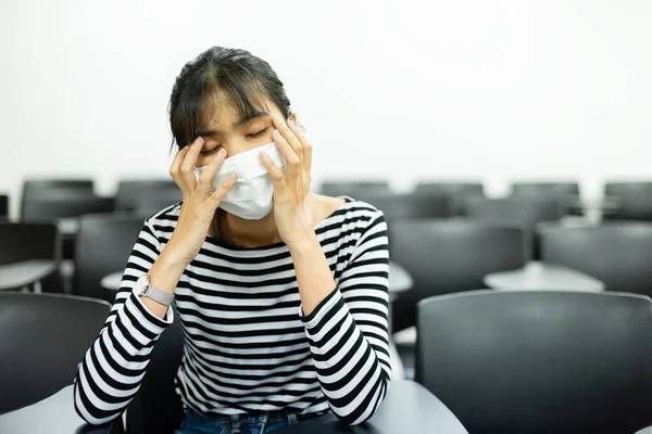 衛生的なマスクを身に着けているアジアの若い女性予防的に病気の症状を持っています 会議室に座って頭痛 — ストック写真